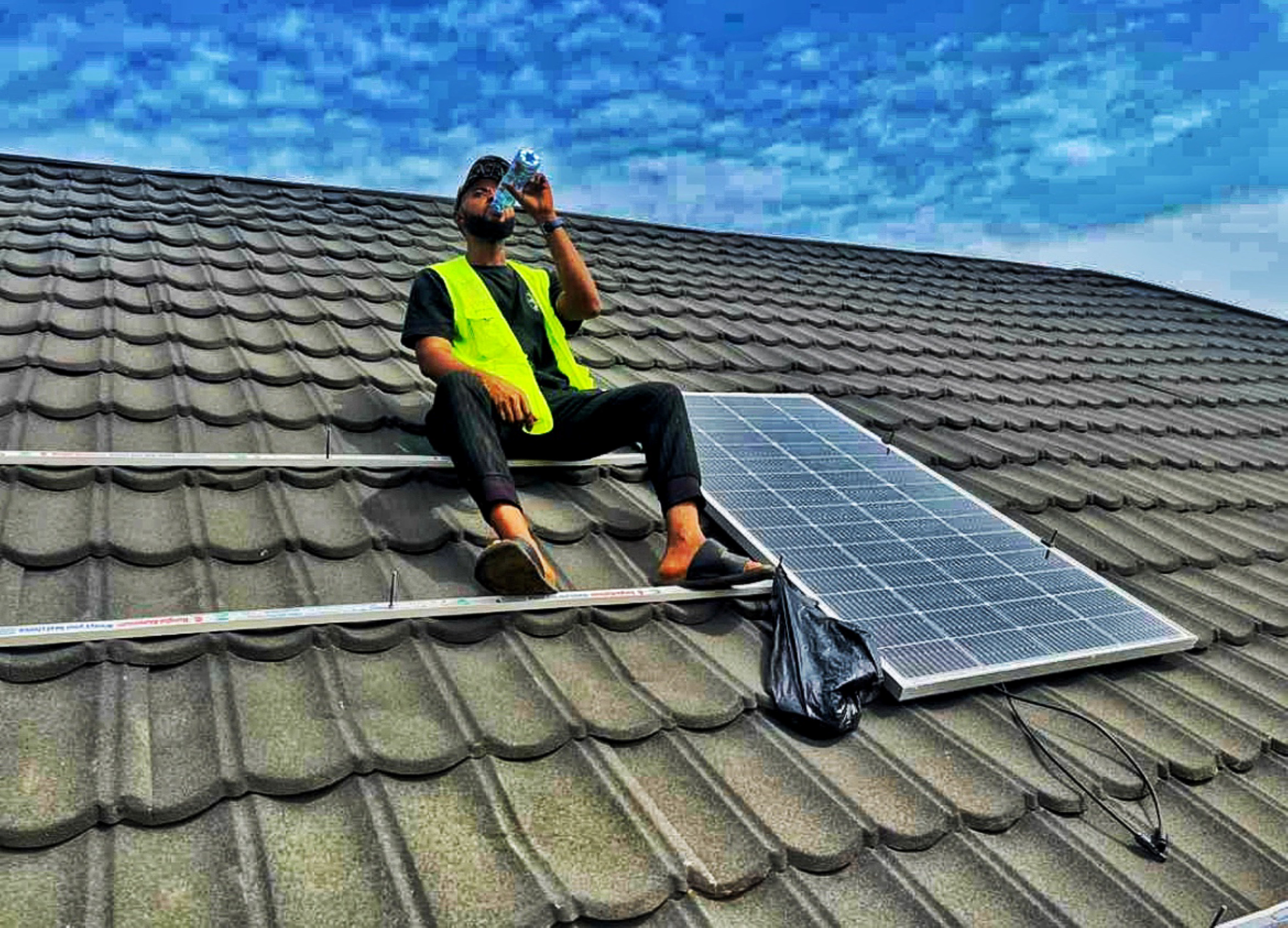Solar installer on a rooftop in Nigeria; editorial photograph
